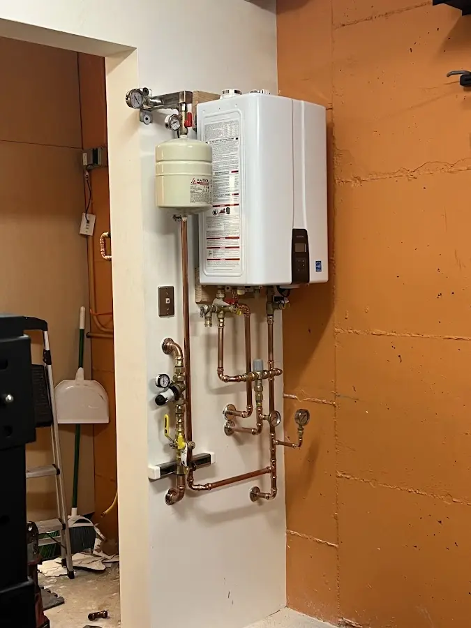 Plumbing technician inspecting water heater connections in New River